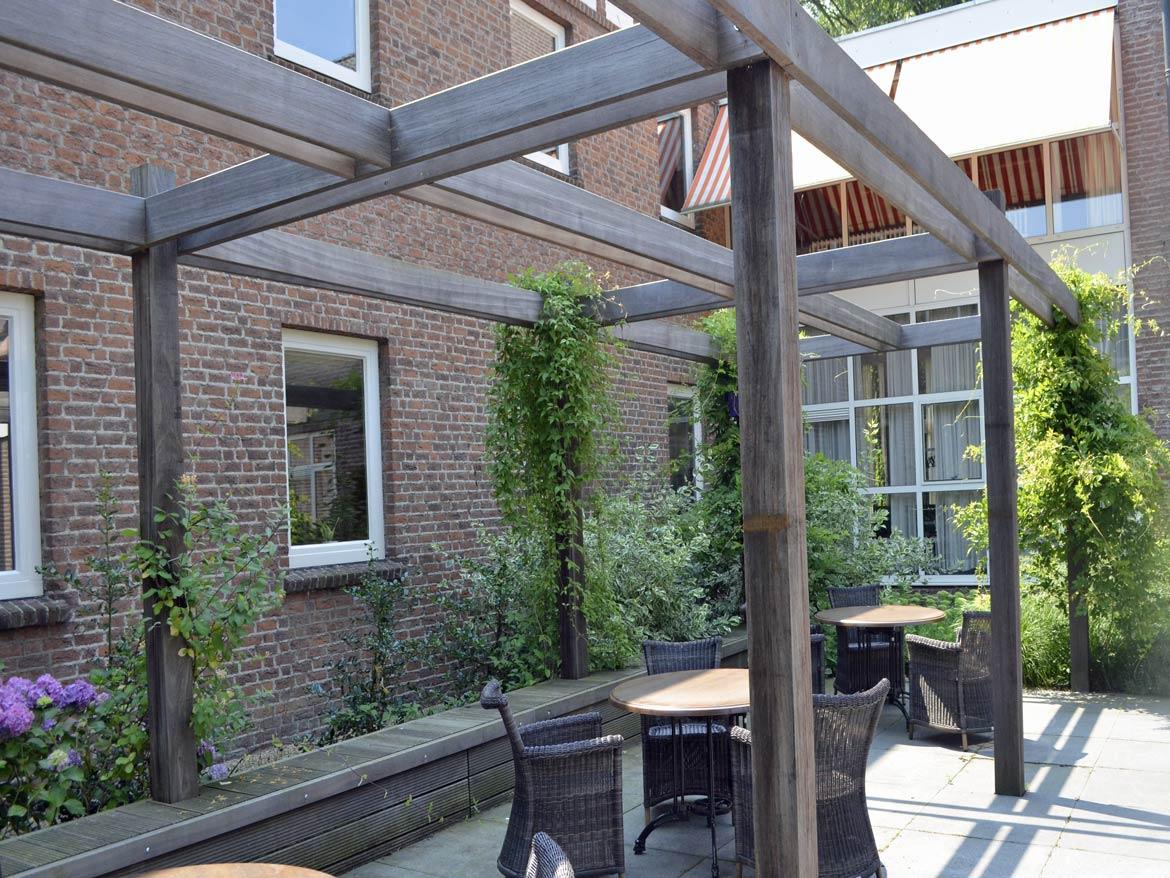 Houten pergola met klimplanten tegen een bakstenen gevel
